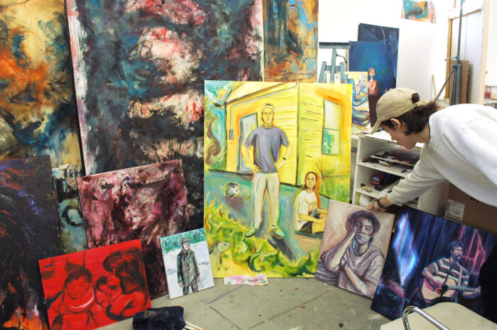 Man displaying several different painted portraits.