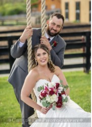 Bride on swing holding flowers with groom behind her