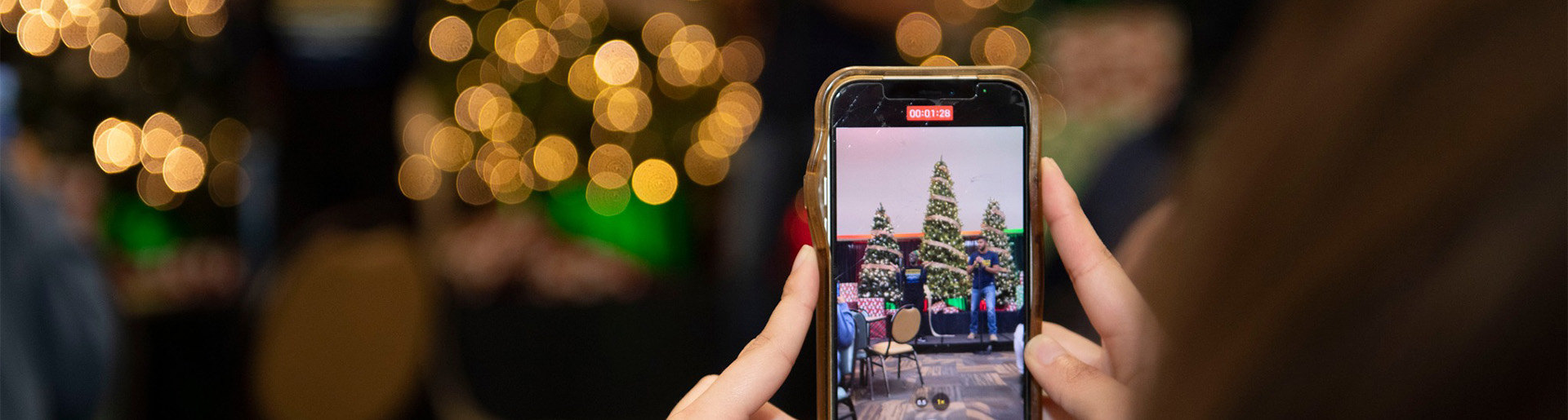 A cell phone displaying an image of 3 decorated Christmas trees.